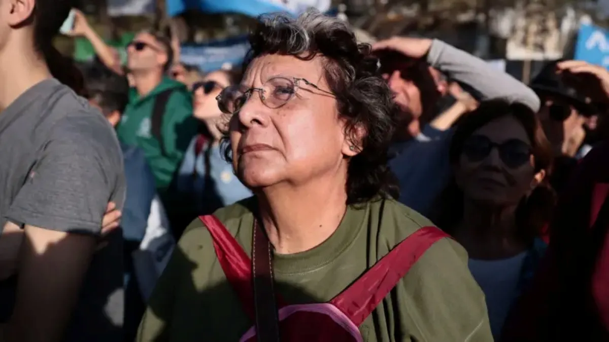 Homem ou mulher com expressão de preocupação, com documentos e contas à frente, representando a pobreza do trabalhador argentino.