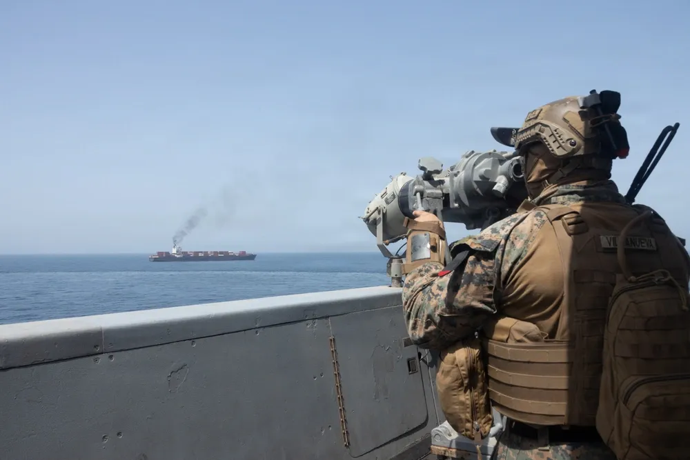 Soldado americano em navio de guerra observando embarcação iraniana em bloqueio