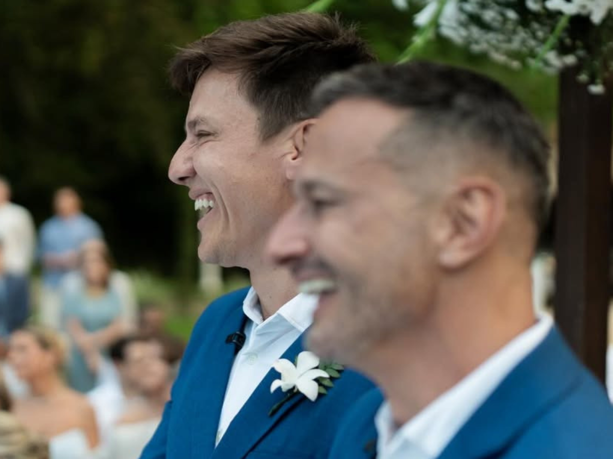 Felipe Suhre e Erick Andrade sorrindo em seu casamento, trocando alianças