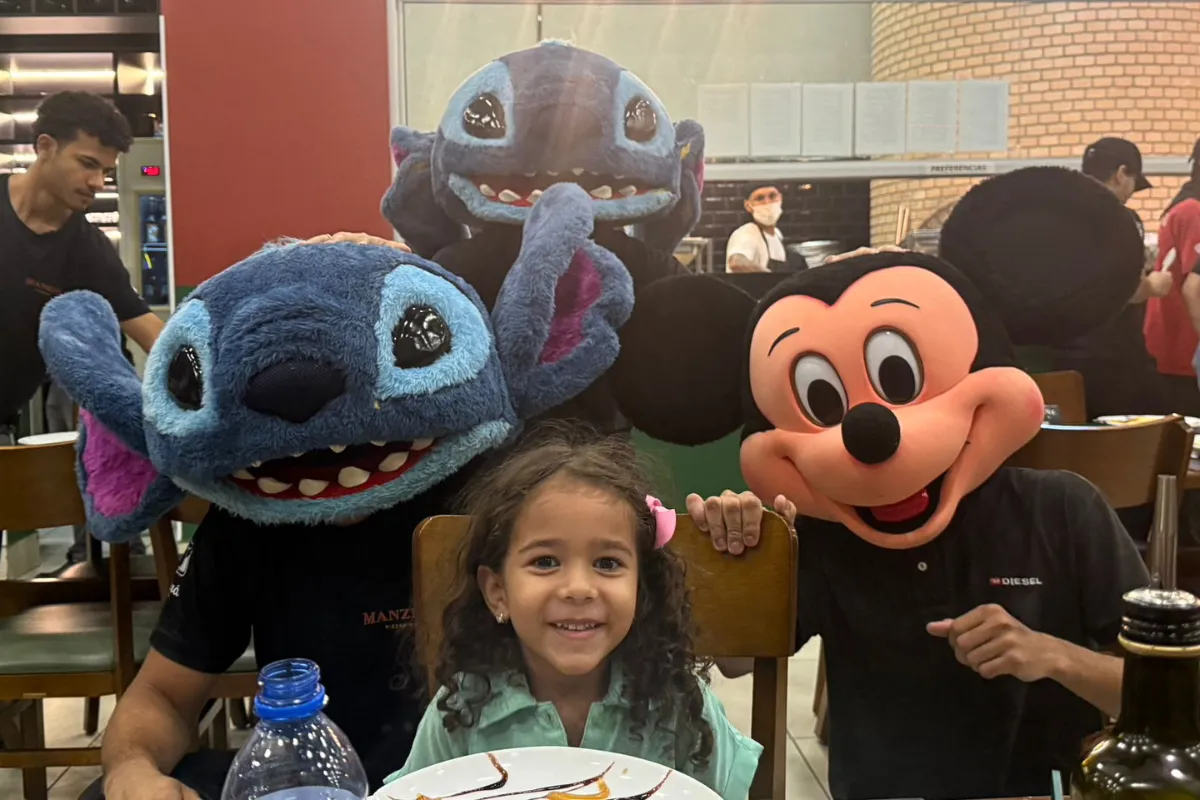 Melina sorrindo e abraçando Stitch e Mickey em seu aniversário