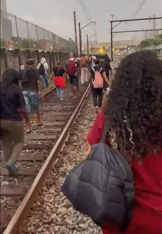 Passageiros caminhando nos trilhos da Linha 11-Coral da CPTM em São Paulo após falha de energia