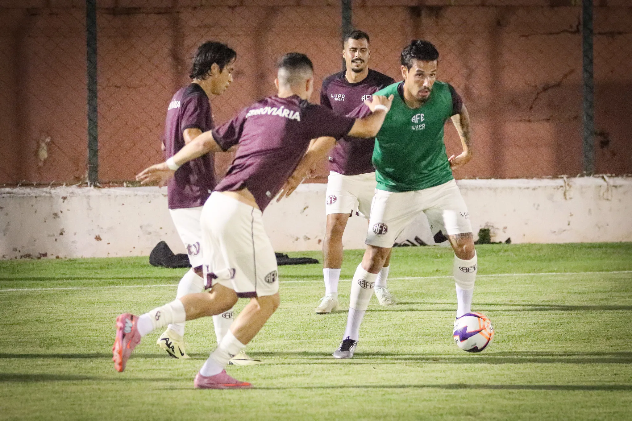 Time da Ferroviária em jogo da Série A2, com uniformes grená, em campo de futebol.