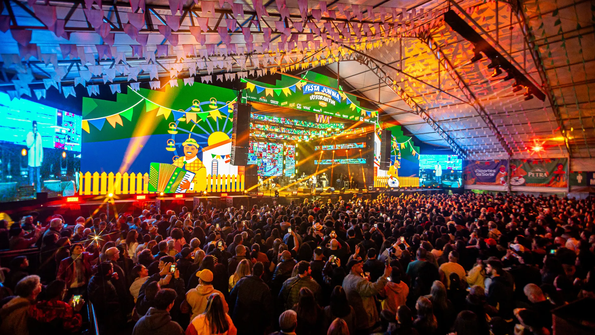 Pessoas com deficiência em área acessível na Festa Junina de Votorantim com bandeirinhas coloridas