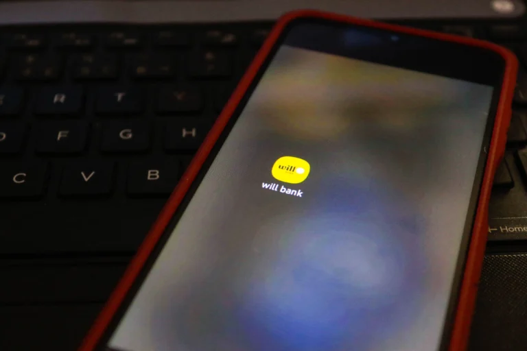 Mãos segurando smartphone com aplicativo do FGC aberto para pagamento Will Bank