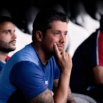 Time do Fortaleza com o técnico Carpini durante uma partida de futebol, torcedores ao fundo.