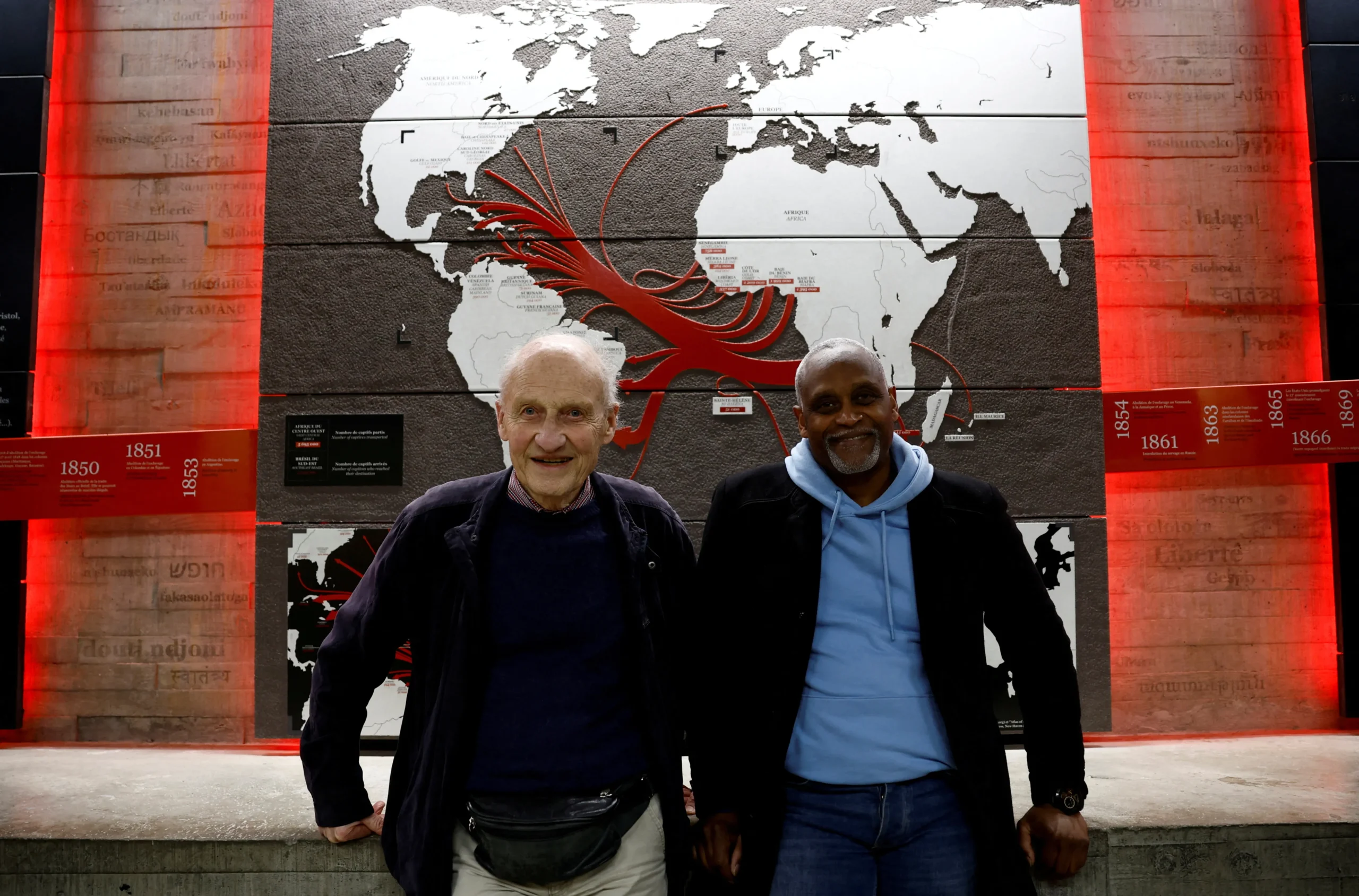 Pierre Guillon de Prince e Dieudonne Boutrin próximos a um mastro de navio em Nantes, simbolizando a reconciliação e o pedido de desculpas pela escravidão.