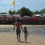 Homem na praia com atestado médico, representando demissão por justa causa