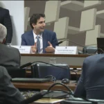 Gabriel Galípolo fala em CPI, com microfones à frente e fundo de plenário.
