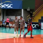 Dois jogadores de futsal idênticos, Alan e Alex, em ação na quadra, mostrando a forte conexão e passes precisos durante a Copa TV Grande Rio de Futsal.