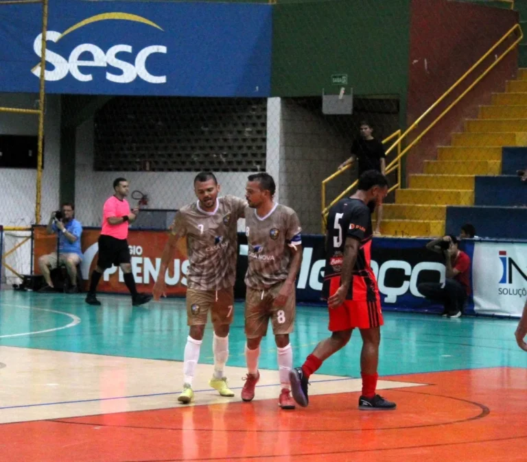 Dois jogadores de futsal idênticos, Alan e Alex, em ação na quadra, mostrando a forte conexão e passes precisos durante a Copa TV Grande Rio de Futsal.