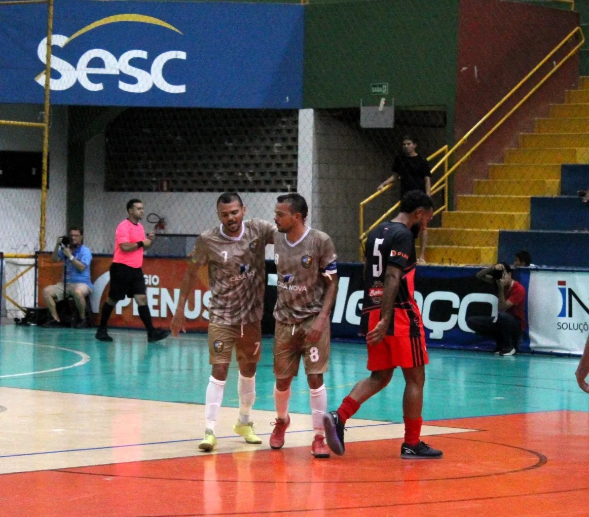 Dois jogadores de futsal idênticos, Alan e Alex, em ação na quadra, mostrando a forte conexão e passes precisos durante a Copa TV Grande Rio de Futsal.