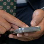 Pessoa olhando para o celular com expressão de preocupação, representando um golpe digital e a necessidade de proteção contra fraudes com inteligência artificial.