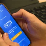 Mãos segurando smartphone com aplicativo de FGTS e dinheiro, simbolizando a liberação de fundos para pagar dívidas.
