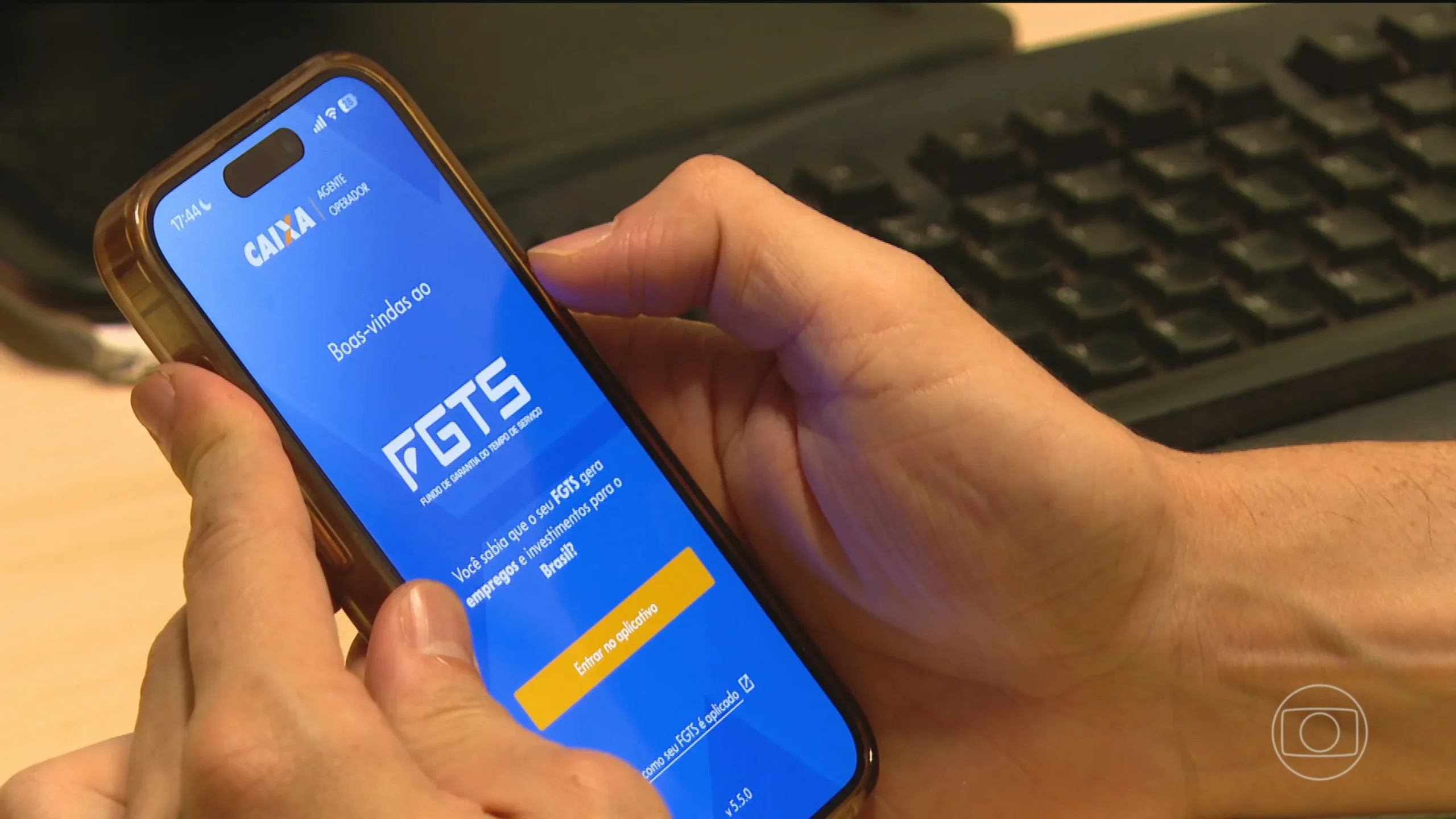 Mãos segurando smartphone com aplicativo de FGTS e dinheiro, simbolizando a liberação de fundos para pagar dívidas.
