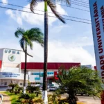 Grupo de servidores técnico-administrativos em greve, com cartazes reivindicando direitos em frente a uma universidade federal.