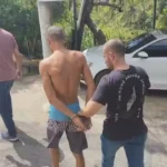 Mão segurando placa 'Denuncie' contra violência de gênero