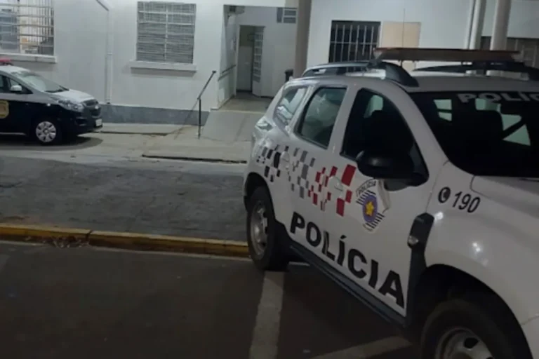 Viatura da Polícia Militar estacionada em rua residencial, com luzes piscando, em Santo Anastácio