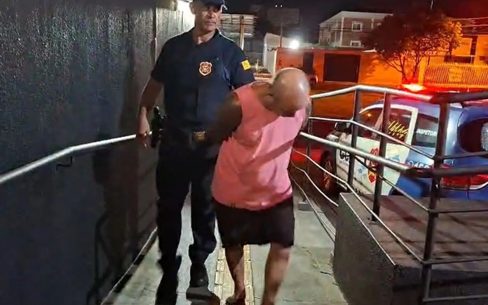 Homem algemado sendo preso pela Guarda Civil em rua escura, Ribeirão Preto