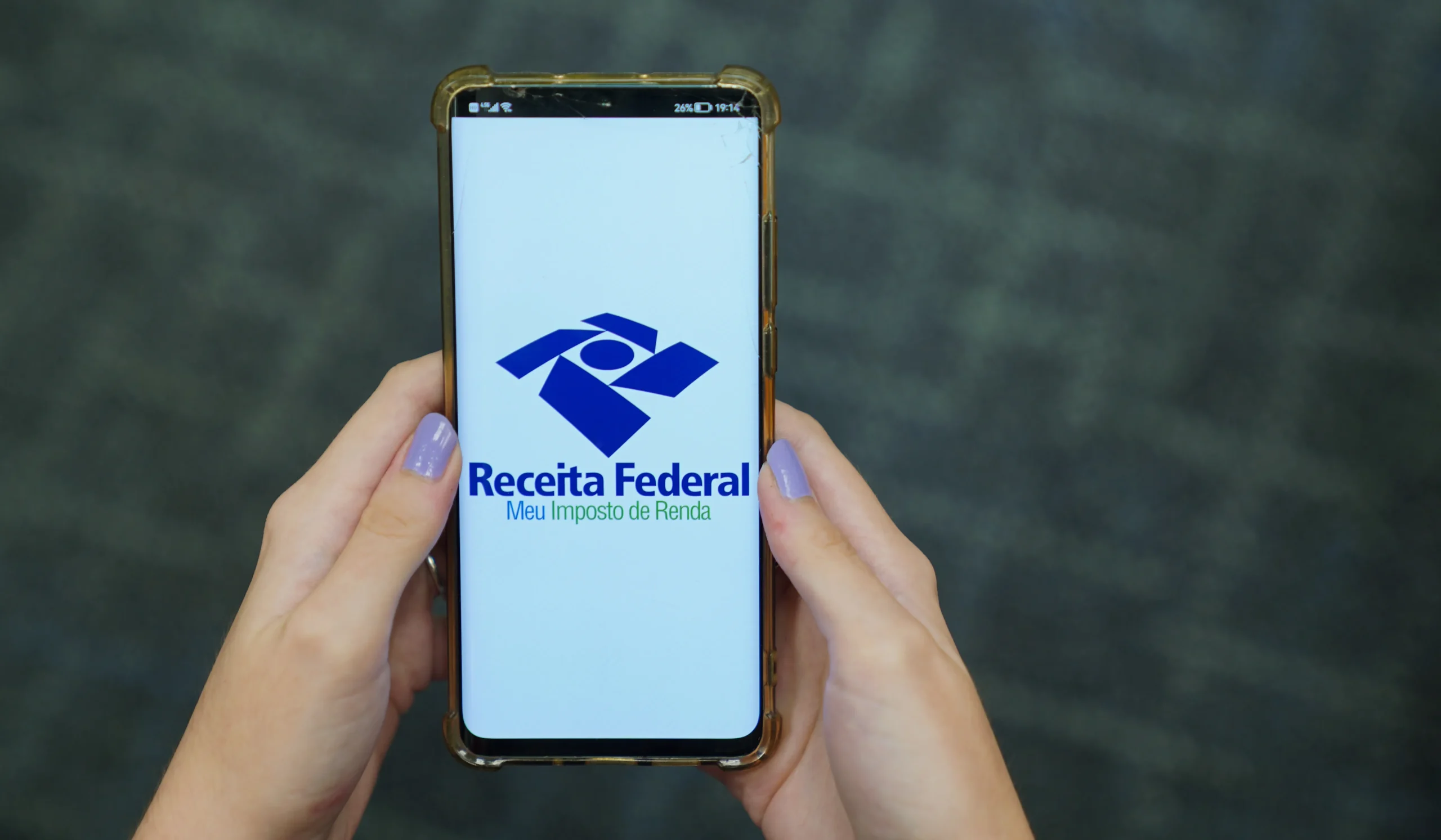 Pessoa preenchendo Imposto de Renda no computador com documentos fiscais