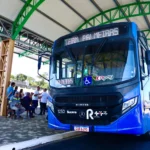Grupo de estudantes universitários e técnicos em Suzano, com mochilas, aguardando transporte público com o Passe Livre Estudantil.