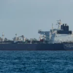 Petroleiro navegando pelo Estreito de Ormuz com navio militar iraniano ao fundo