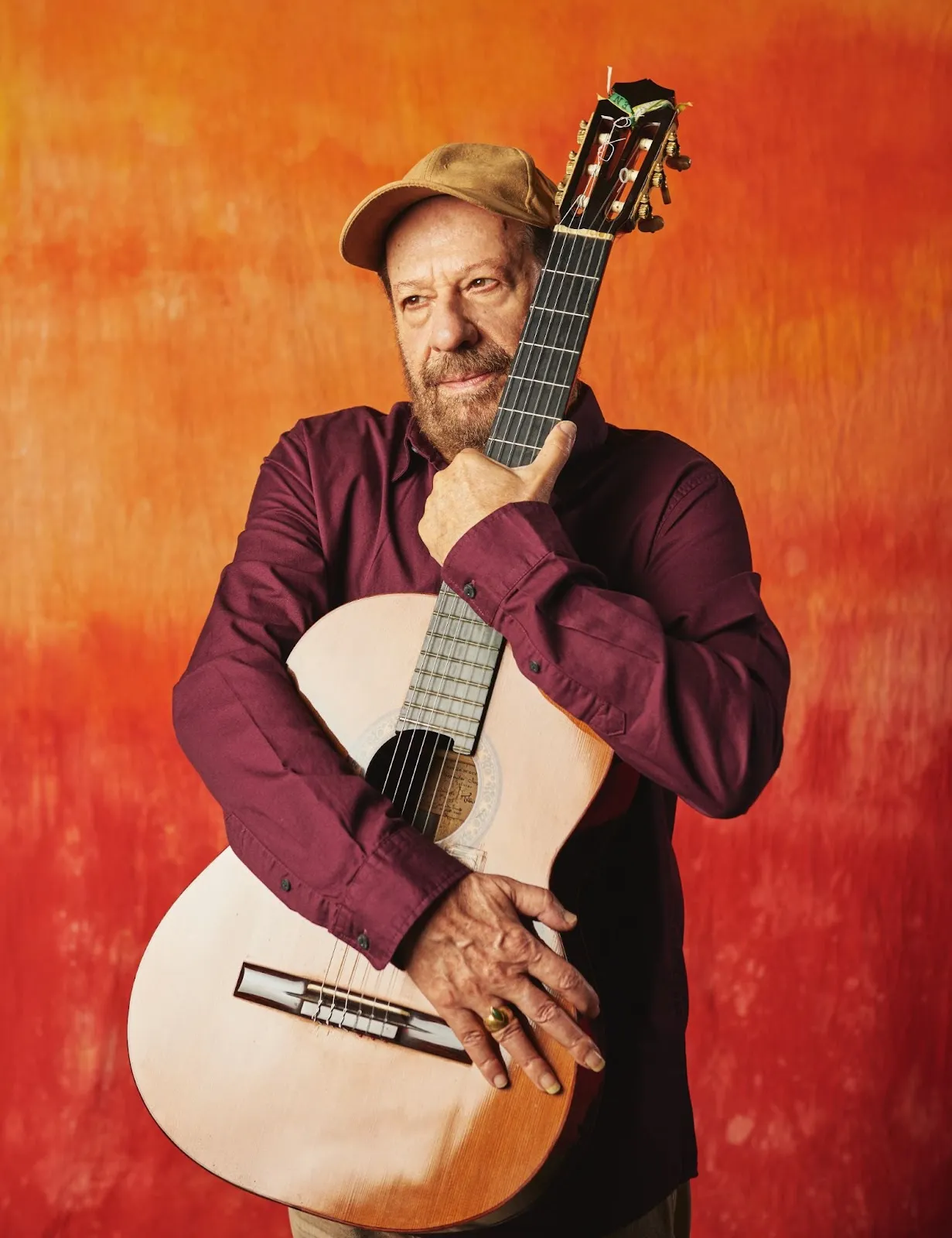 João Bosco tocando violão e sorrindo, celebrando seus 80 anos e novo álbum.