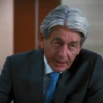 John Nolan em cena de filme Batman, com expressão séria