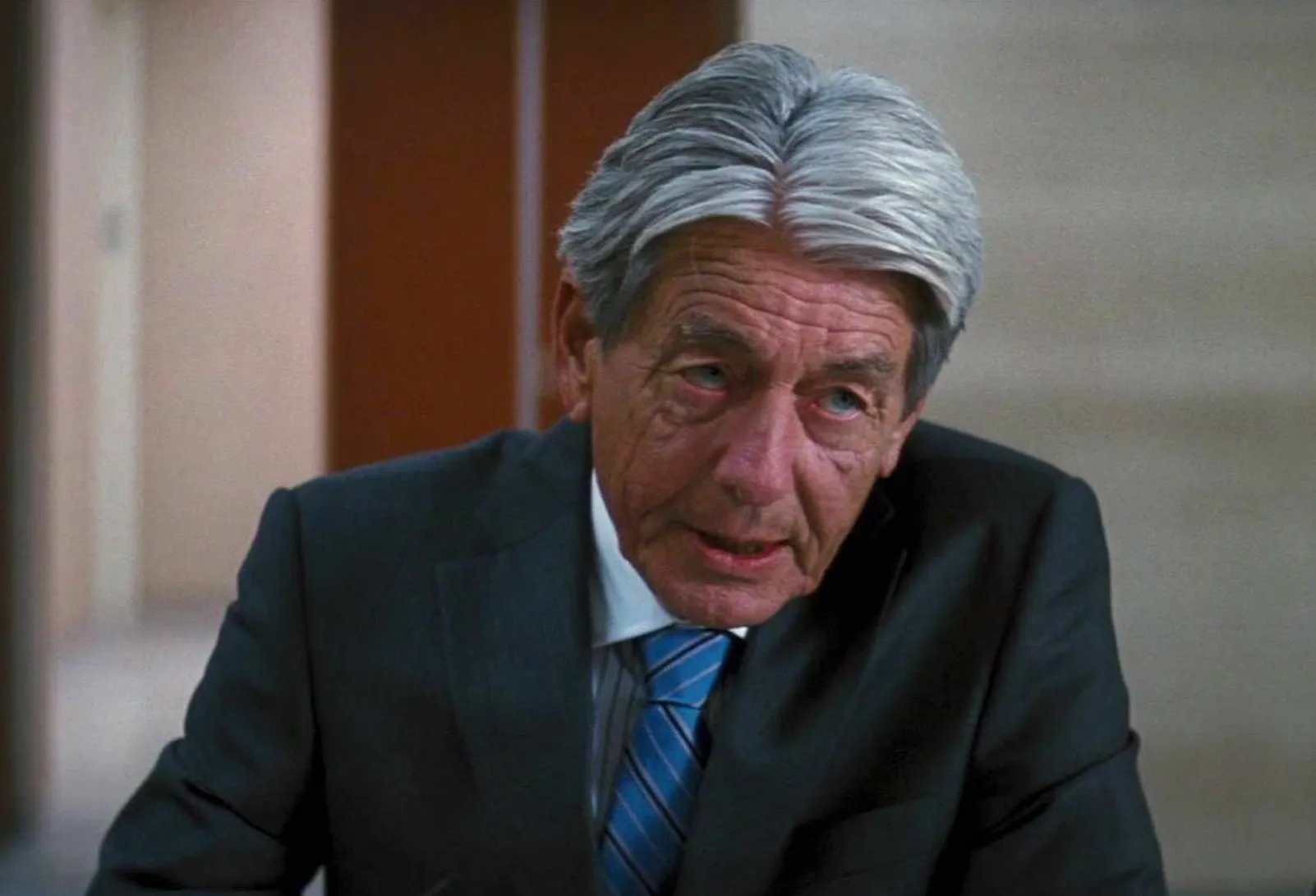 John Nolan em cena de filme Batman, com expressão séria