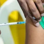 Panfleto de vacinação contra gripe em Jundiaí com fundo de unidade de saúde