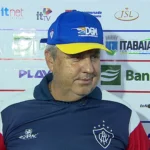 Gilson Kleina, técnico do Itabaiana, em pé à beira do campo durante uma partida de futebol