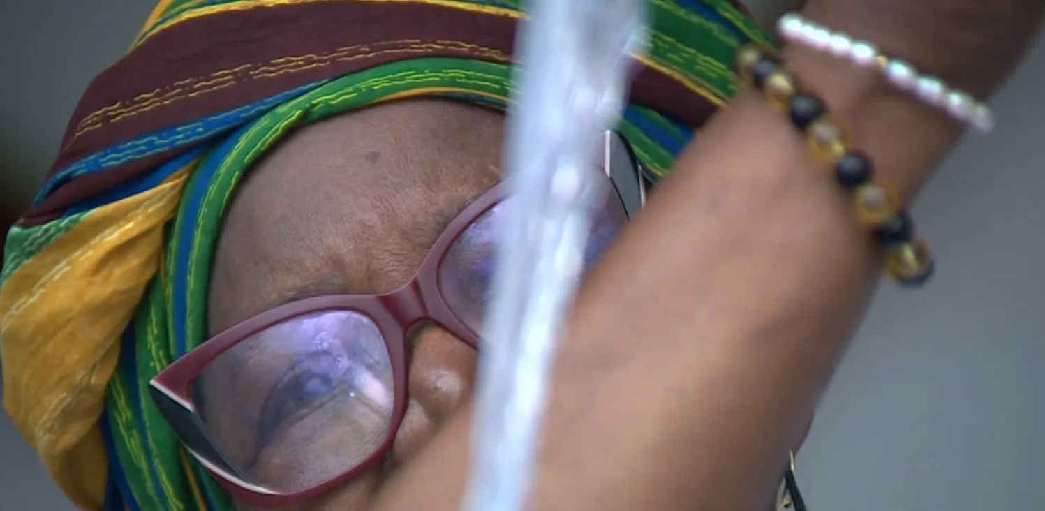 Mulheres vestidas de branco durante a Lavagem da Escadaria da Catedral de Campinas, jogando água e flores nos degraus da catedral.