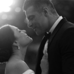 Lissa Martins cantando no palco, com lágrimas nos olhos, enquanto sua filha Antonella, de 8 anos, a observa da plateia e oferece um lencinho.