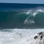 Surfista Lucas Chumbo caindo em onda gigante australiana perto das pedras