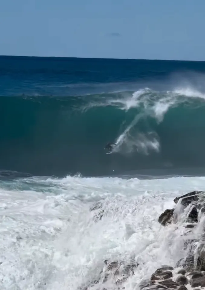 Surfista Lucas Chumbo caindo em onda gigante australiana perto das pedras