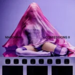 Madonna dançando em palco iluminado, celebrando o lançamento de Confessions II