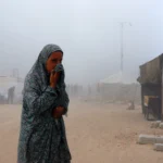 Mulher palestina em Gaza após bombardeio cobrindo o rosto