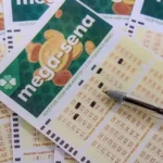 Mãos segurando um bilhete da Mega-Sena com os números sorteados e um fundo desfocado de uma lotérica movimentada.