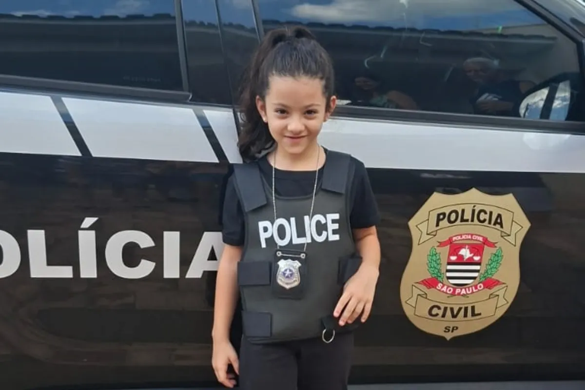 Criança feliz com policiais civis em sua festa de 7 anos