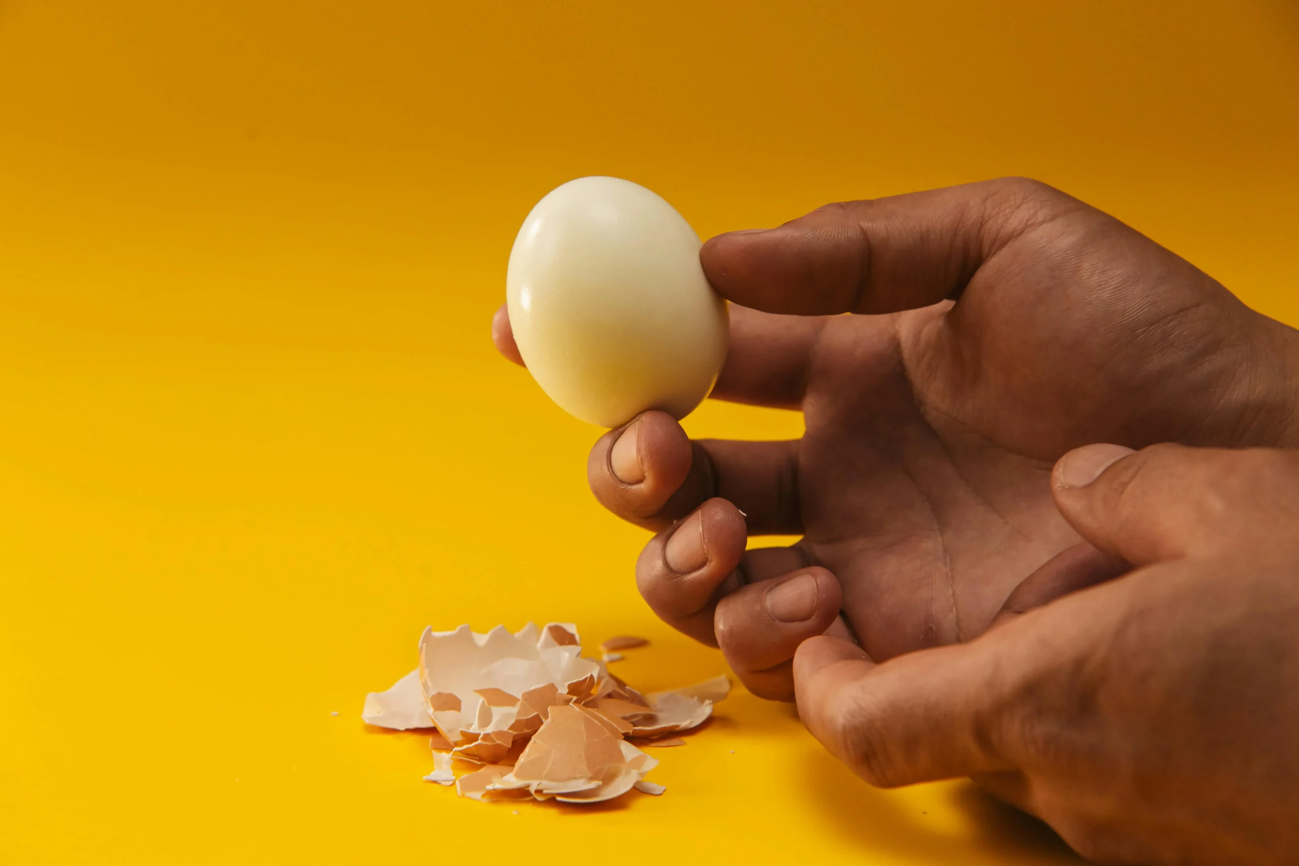 Mulher lavando alface na pia da cozinha, com frango cru em uma tábua ao lado, representando a necessidade de cuidado para não lavar carne e evitar contaminação.