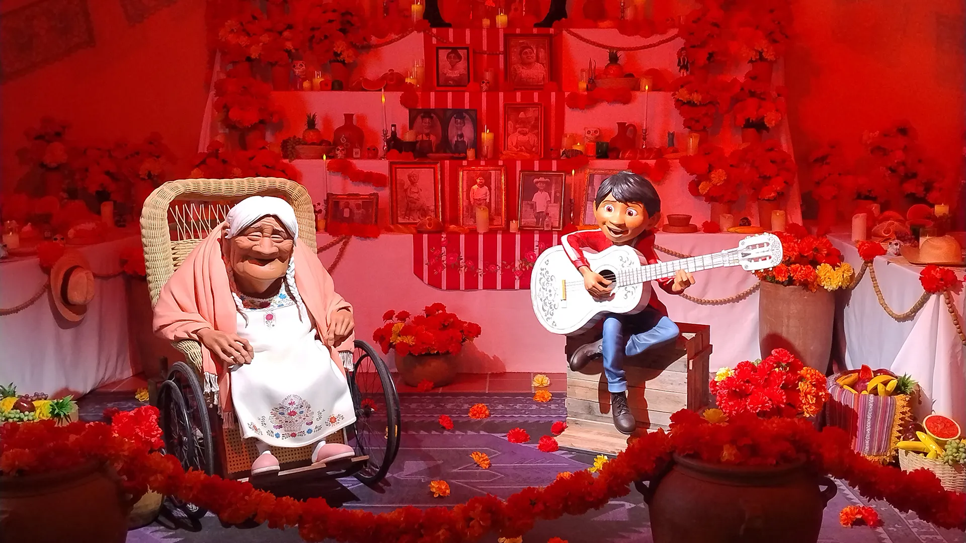 Pessoas interagem com estátuas de personagens e cenários de filmes Pixar na exposição Mundo Pixar no Rio