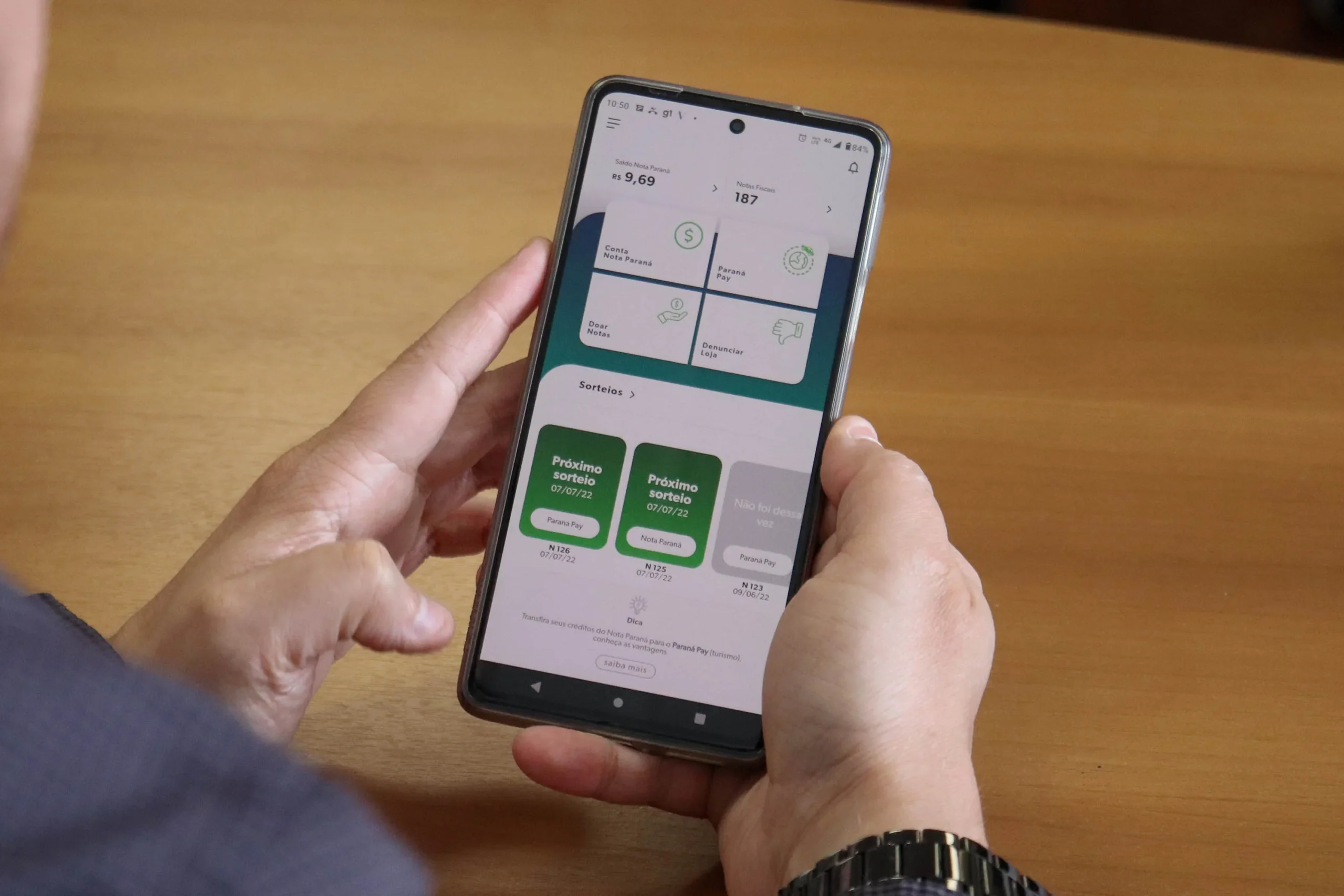 Smartphone exibindo o aplicativo Nota Paraná com notas fiscais e prêmios em dinheiro, representando a participação e ganhos no programa