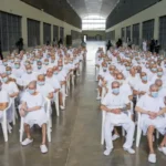 Tribunal com telas de videoconferência para julgamento coletivo de membros da gangue MS-13 em El Salvador.