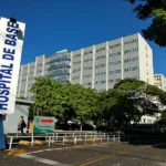 Homem idoso recebendo injeção de vacina no braço por enfermeira em hospital, representando pesquisa de nova vacina contra gripe.