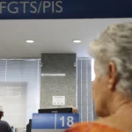 Mão segurando celular consultando PIS/Pasep