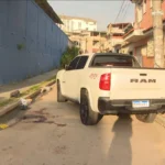 Rua na Pavuna com luzes de polícia ao fundo, representando o local da morte do empresário Daniel