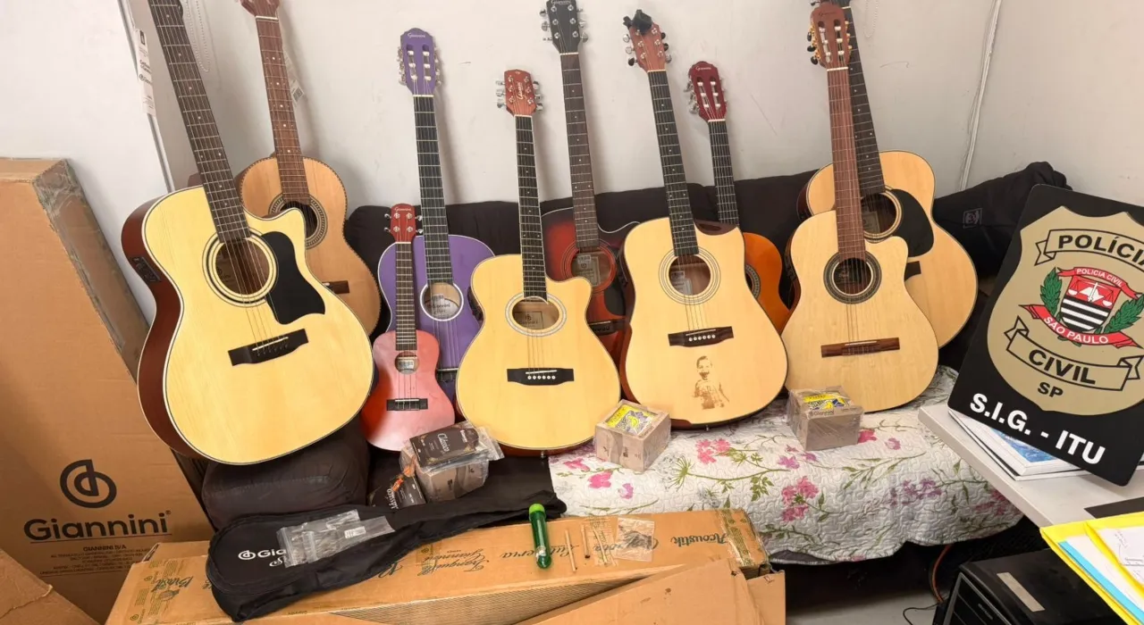Policiais civis inspecionando instrumentos musicais recuperados, como violões e ukuleles, após furto em fábrica de São Paulo.
