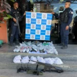Policiais com réplica de fuzil e drogas apreendidas em Maricá