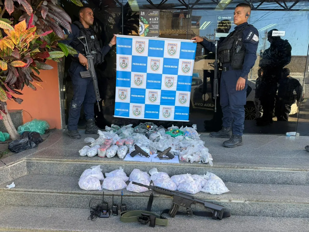 Policiais com réplica de fuzil e drogas apreendidas em Maricá