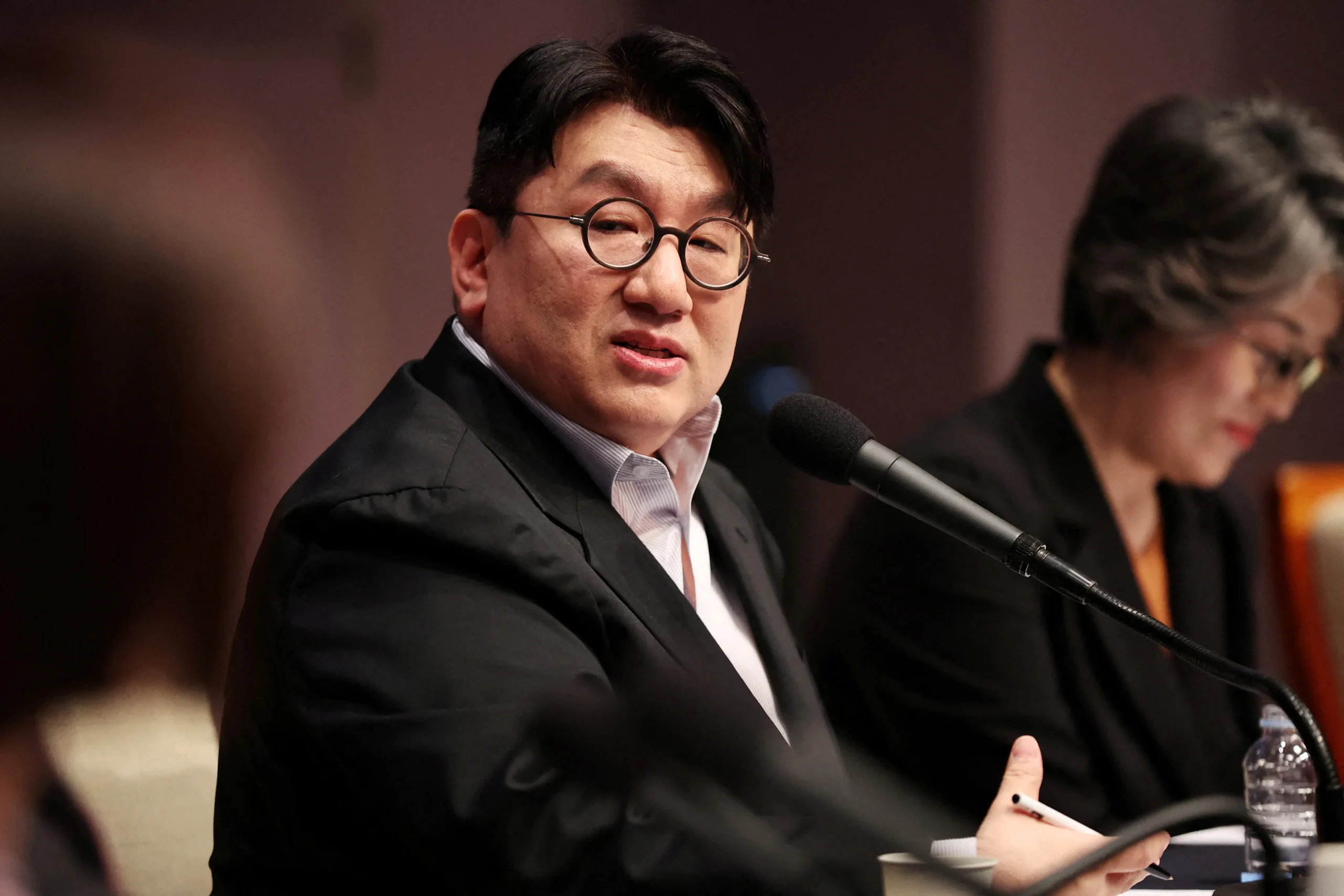 Bang Si-hyuk, fundador da Hybe, agência do BTS, enfrentando acusações de lucros ilegais e pedido de prisão.