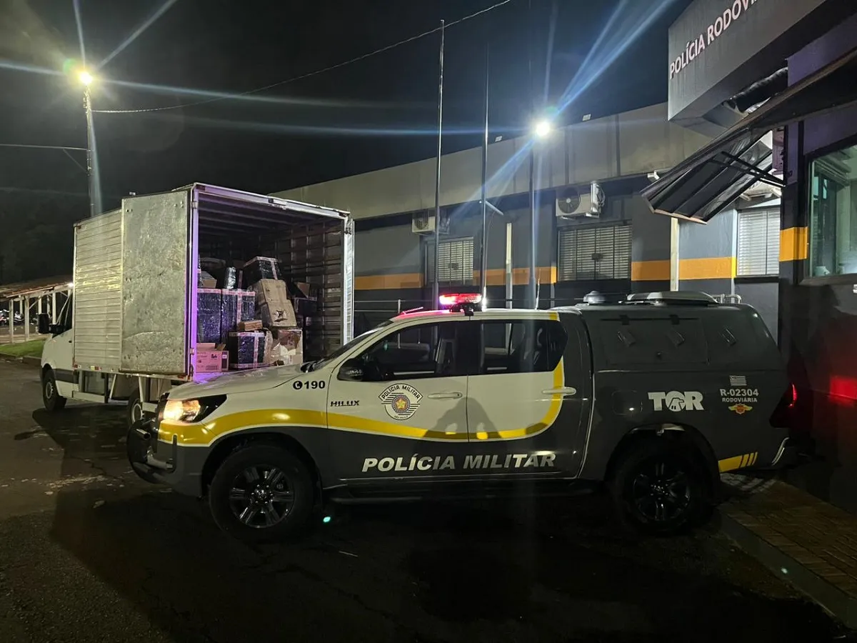 Policiais inspecionando uma grande apreensão de eletrônicos ilegais em van na rodovia.